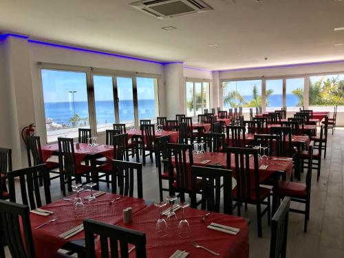 a dining room with red tables and chairs and the ocean at First Flatotel International in Benalmádena