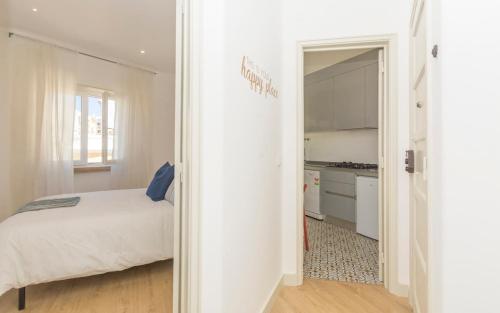 リスボンにあるHappy Daysの白いベッドルーム(ベッド1台付)、キッチンが備わります。