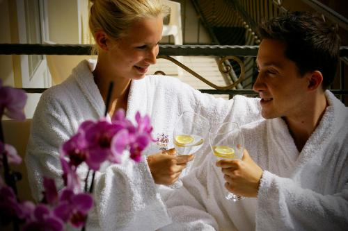 a man and a woman in towels drinking wine at Xavin Wellness Hotel & Restaurant in Harkány
