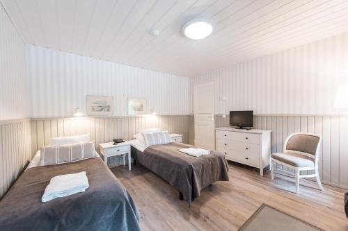 a bedroom with two beds and a tv and a chair at Hotelli Messilä in Lahti