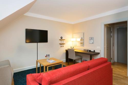 a living room with a red couch and a desk at ProfilHotels Riddargatan in Stockholm