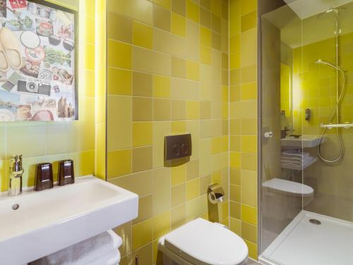 uma casa de banho com lavatório, WC e azulejos amarelos em the niu Dairy em Haarlem