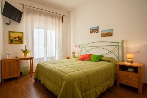 una camera con letto verde e finestra di B&B Pleiadi a San Vito lo Capo