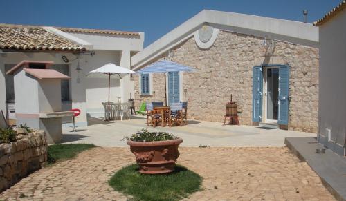 a courtyard with a patio with a table and an umbrella at Casa vacanze La Meridiana in Donnalucata