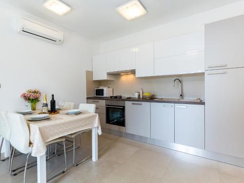 a kitchen with white cabinets and a table with chairs at Apartments Gioia in Poreč