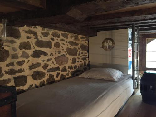 een bed in een kamer met een stenen muur bij Le 1684 in Saint-Malo