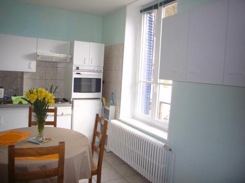 a kitchen with a table with a vase of flowers on it at Aux Studios du Parc in Plombières-les-Bains