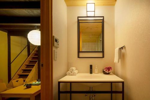 a bathroom with a sink and a mirror and a staircase at Kumashu an Machiya House in Kyoto