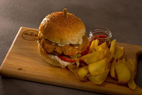 a hamburger and potato chips on a wooden board at Aparthotel Punta Blu - POOL & SPA in Premantura