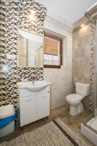 La salle de bains est pourvue de toilettes, d'un lavabo et d'un miroir. dans l'établissement Apartamenty U Zajaców, à Zakopane