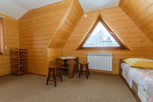 Cette chambre mansardée comprend un lit et une fenêtre. dans l'établissement Apartamenty U Zajaców, à Zakopane