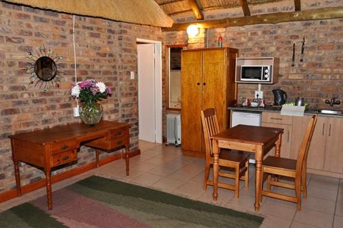 a kitchen with a wooden table and chairs and a table and a tablektop at Tranquillity Day Spa & Lodge in Baviaanspoort