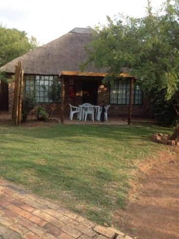 a house with a table and chairs in the yard at Tranquillity Day Spa & Lodge in Baviaanspoort