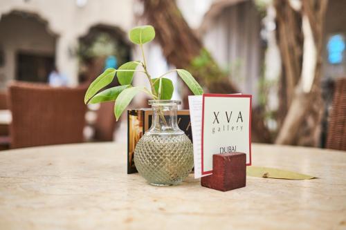 a vase sitting on top of a table with a card and a book at XVA Art Hotel in Dubai