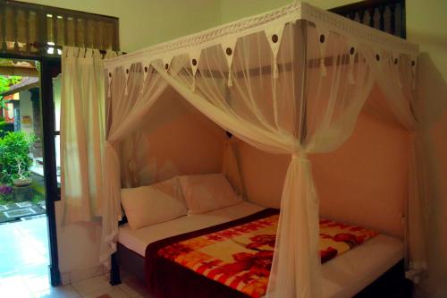 a bedroom with a canopy bed with white curtains at Yumi House in Ubud