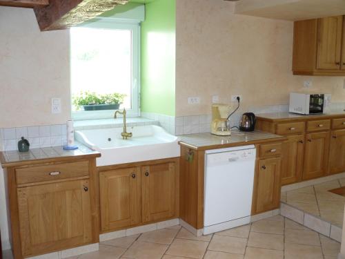 eine Küche mit Holzschränken, einem Waschbecken und einem Fenster in der Unterkunft Gîte de la sauge in Mignovillard