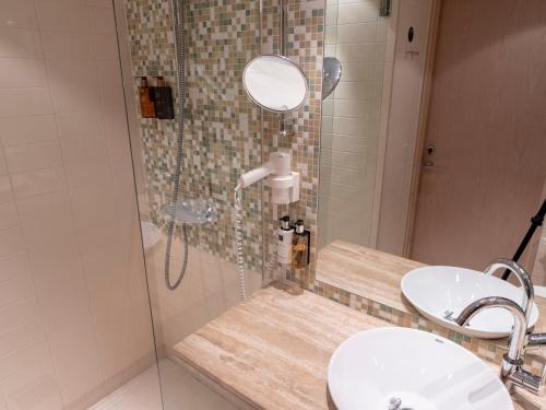 a bathroom with a shower with two sinks and a mirror at Clarion Hotel Sign in Stockholm