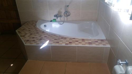a bath tub in a bathroom with a tile floor at Tranquillity Day Spa & Lodge in Baviaanspoort