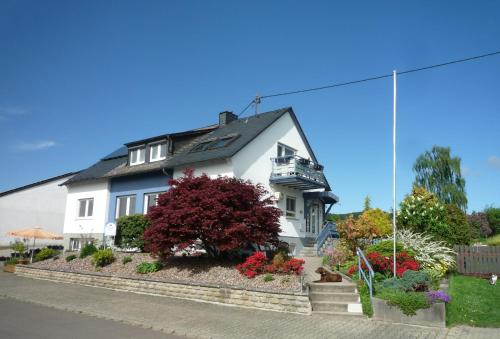ein weißes Haus mit einem blühenden Busch davor in der Unterkunft Ferienwohnungen Engelsgaertchen in Oberwesel