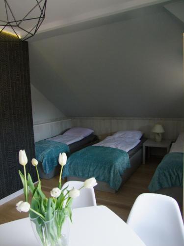 a room with two beds and a vase of flowers on a table at U Henriety in Wojnowice