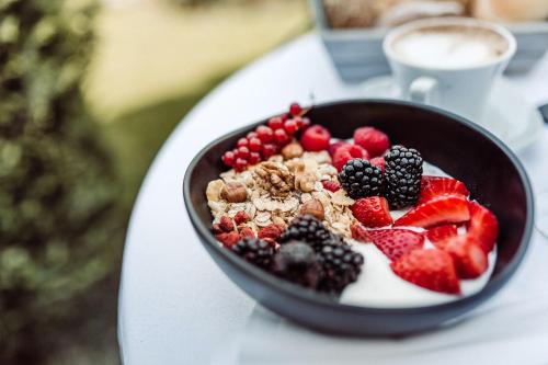 a bowl of fruit on a table with a cup of coffee at Hotel Castel Rundegg (Adults Only) in Merano