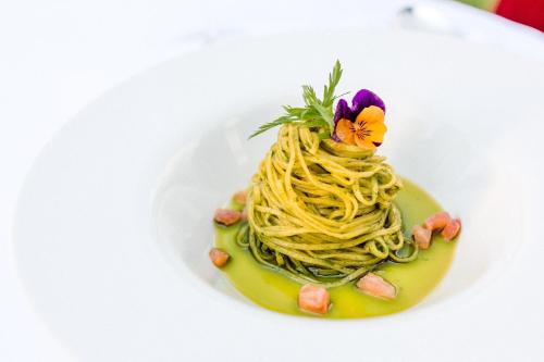 a plate of pasta with a flower on it at Hotel Castel Rundegg (Adults Only) in Merano
