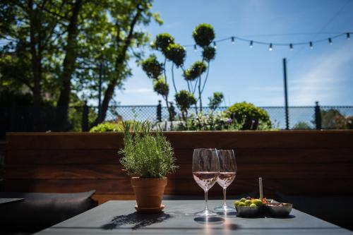 a table with two wine glasses and a potted plant at Hotel Du Vin Stratford in Stratford-upon-Avon