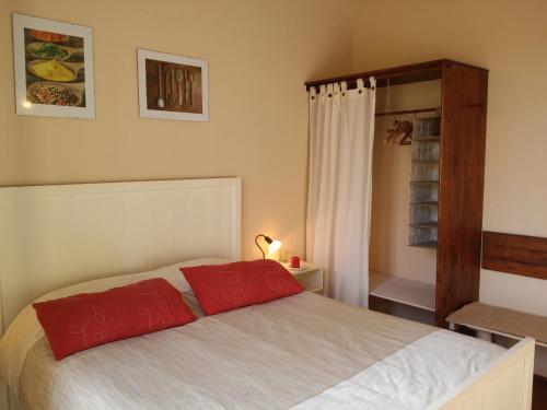 a bedroom with a bed with two red pillows at Finca La Penúltima-Posada in San Rafael