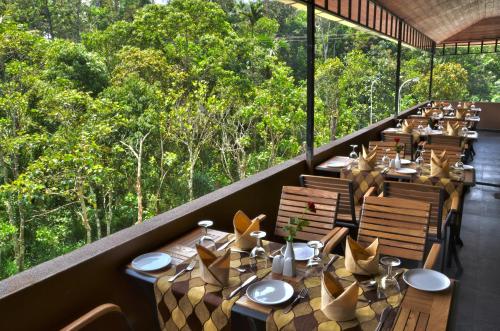 a restaurant with tables and chairs with trees in the background at Spice Grove in Thekkady
