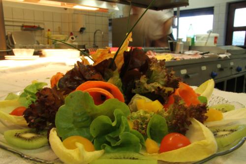 a plate of vegetables on a table in a kitchen at Hotel Schneider in Winterberg