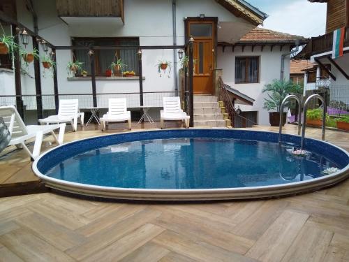 a pool in a yard with chairs and a house at Guest House Unika in Tryavna