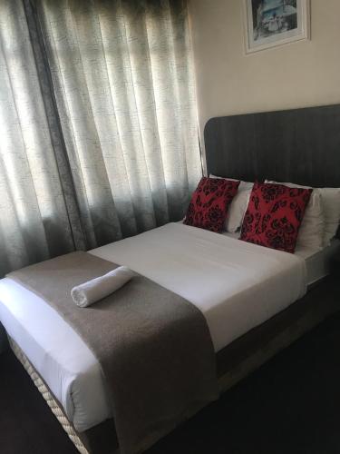 a bed with red pillows sitting in front of a window at Businessburg Hotel in Johannesburg