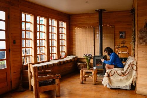 a woman sitting in a chair in a room at Palafito Hostel Chiloé in Castro