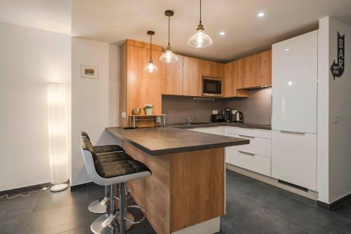 une cuisine avec des placards en bois et un bar avec un tabouret dans l'établissement Wonderful one bedroom heart of Cannes, 2min walk to Carlton hotel!, à Cannes