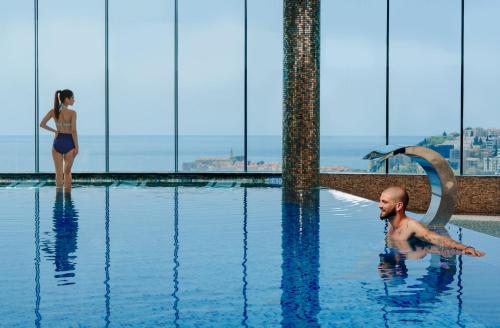 a man in a swimming pool with a woman in the background at Apartments Menuet in Budva