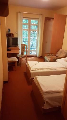 a bedroom with two beds and a tv and a window at hostel leśny in Sopot