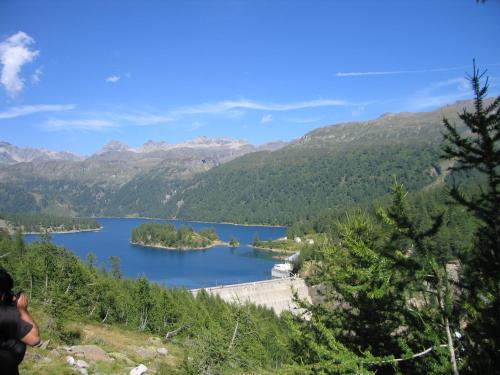a person taking a picture of a lake in the mountains at Tana del Paradiso in Baceno