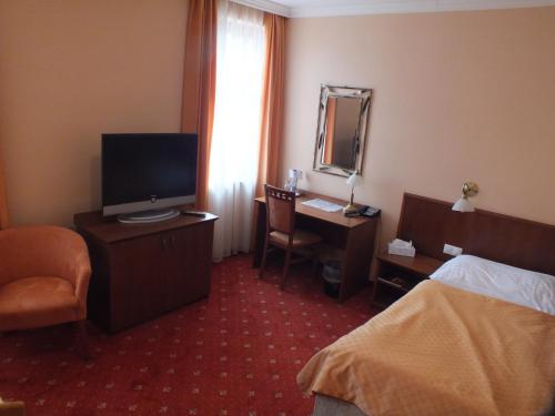 a hotel room with a bed and a desk and a television at Hotel Majolika in Modra