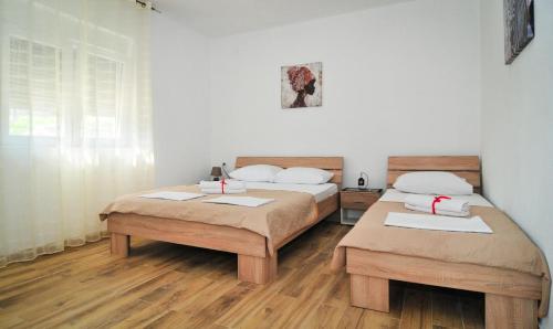 ティヴァトにあるApartmani Bekonjaの木製の床の部屋にベッドが2つあります