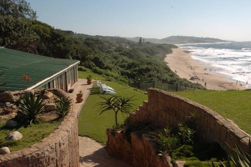 a retaining wall next to a beach with a building at Summer Place Umzumbe in Umzumbe