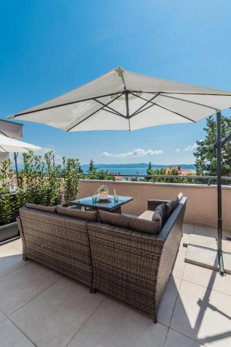 a patio with a couch and an umbrella at Apartments Bego Spa & Wellness in Crikvenica