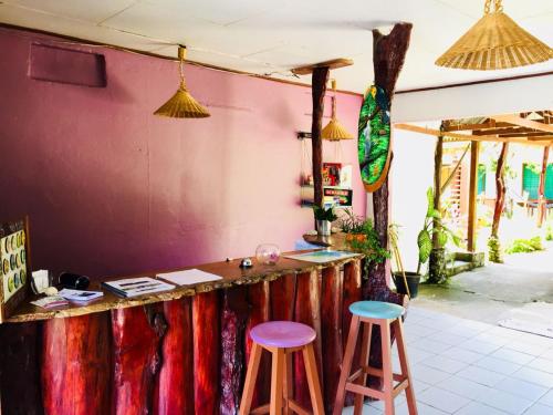 a bar with two stools in front of a pink wall at Cabinas Palmer Makanda in Cahuita
