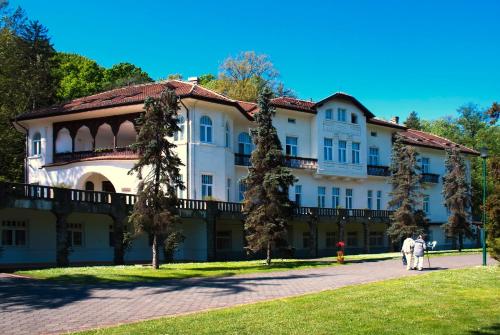 a building with two people walking in front of it at Apartman A9 Lux in Banja Koviljača