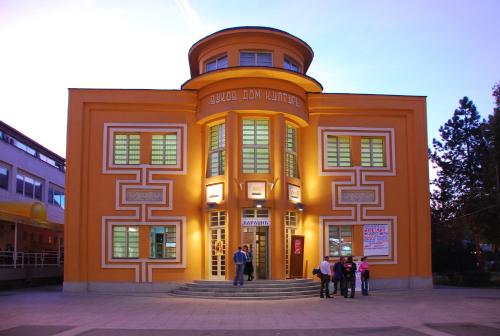 an orange building with people standing in front of it at Apartman A9 Lux in Banja Koviljača