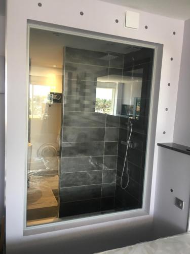 La salle de bains est pourvue d'une douche et de carrelage noir. dans l'établissement Village Naturiste Agde, au Cap d'Agde