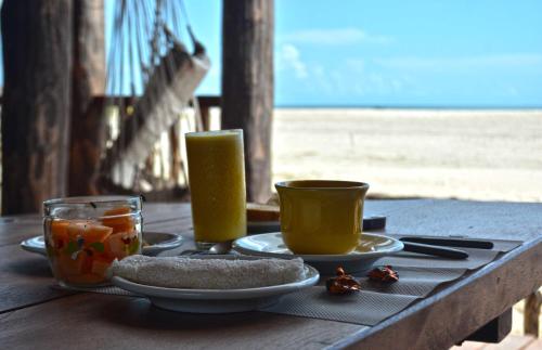 a table with two cups and a plate of food at Casa Dunas da Barrinha in Barrinha