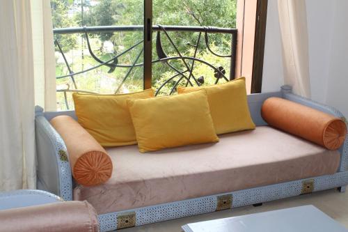 un sofá con almohadas sentado frente a una ventana en La Fontaine, en Marrakech
