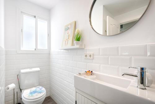 a white bathroom with a toilet and a mirror at Beachside cosy apartment with pool in Estepona