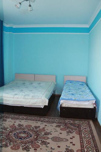 two beds in a room with blue walls and a rug at Гостевой дом "Светлана" in Cholpon-Ata