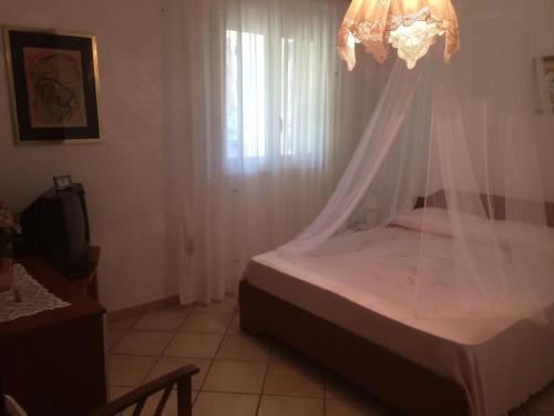 ein Schlafzimmer mit einem Bett mit einem Vorhang und einem Kronleuchter in der Unterkunft Villetta Vacanza in Carovigno